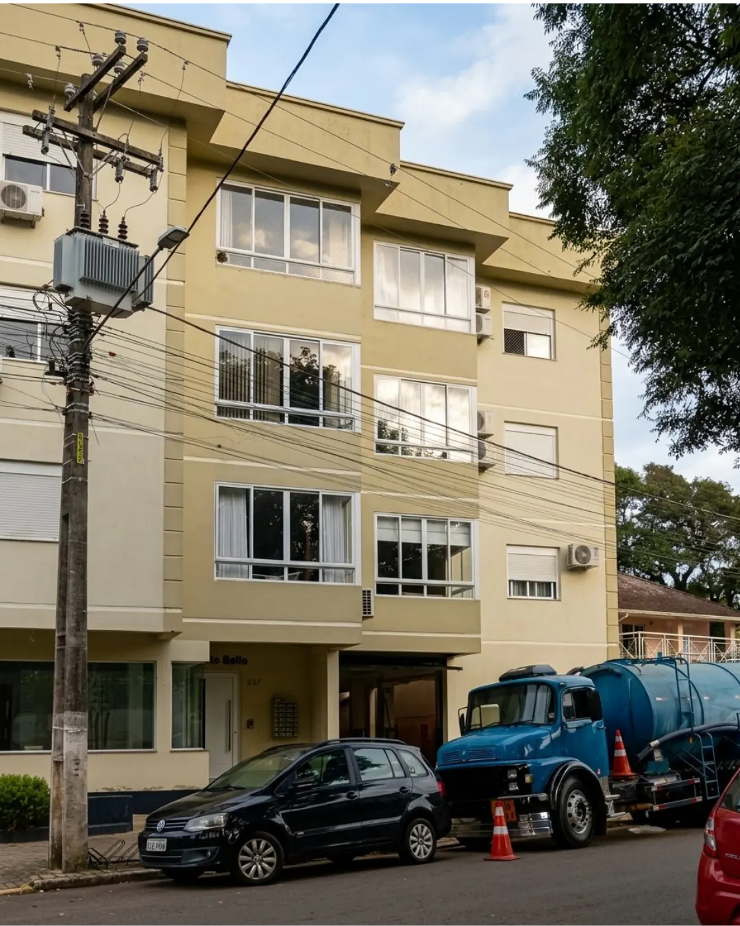 Caminhão auto vácuo azul em frente a prédio residencial
